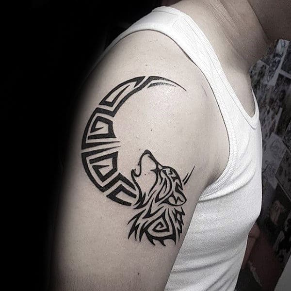 Man With Tattoo Of Tribal Wolf And Moon On Upper Arm