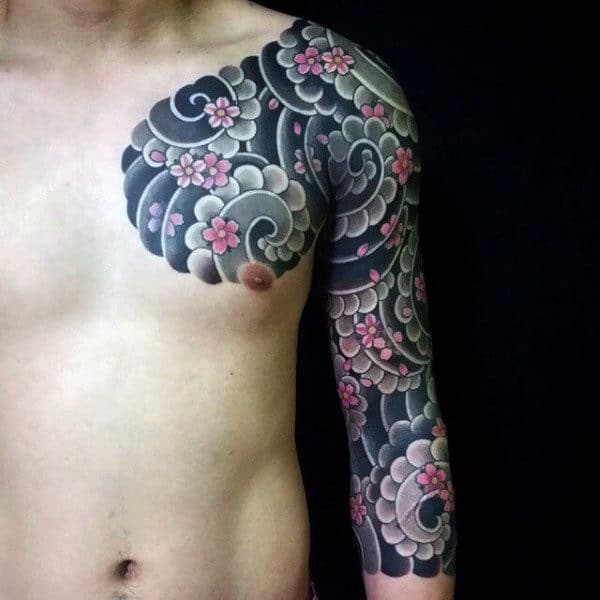Person with a detailed black and gray tattoo sleeve featuring pink cherry blossoms on the arm and chest