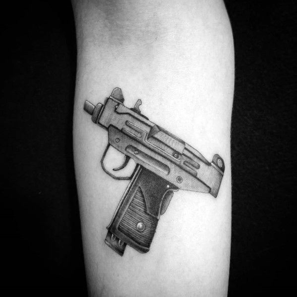 Black and grey Uzi tattoo on the forearm with fine shading and realistic details, creating a bold and striking firearm design.