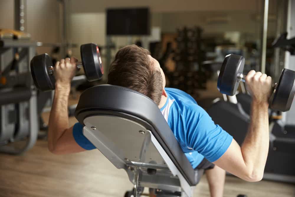 man incline dumbbell bench press works out in gym