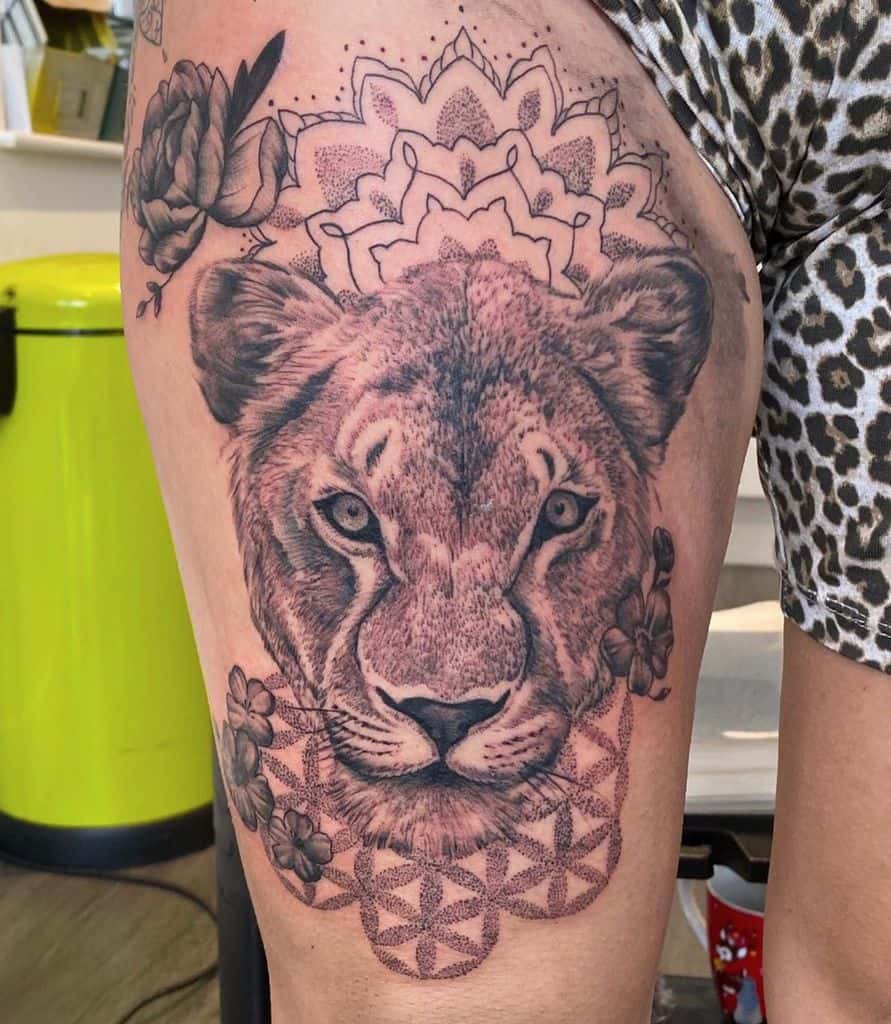 Realistic lioness thigh tattoo with intricate dotwork mandala and geometric patterns, blending strength and spirituality in a bold design.