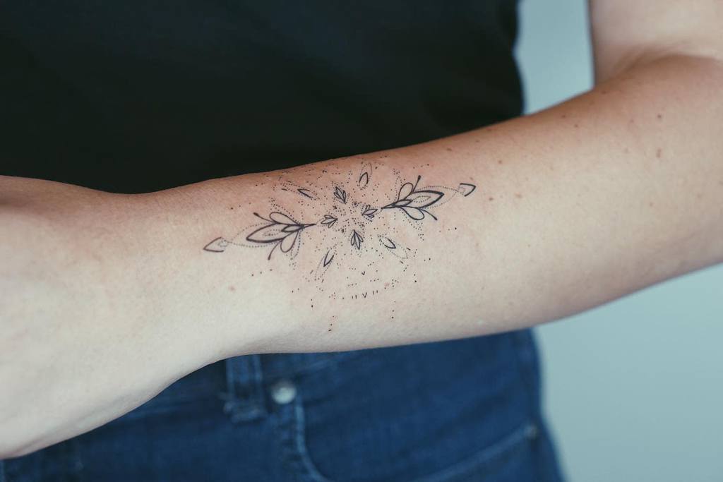 A forearm with a detailed geometric and floral tattoo design
