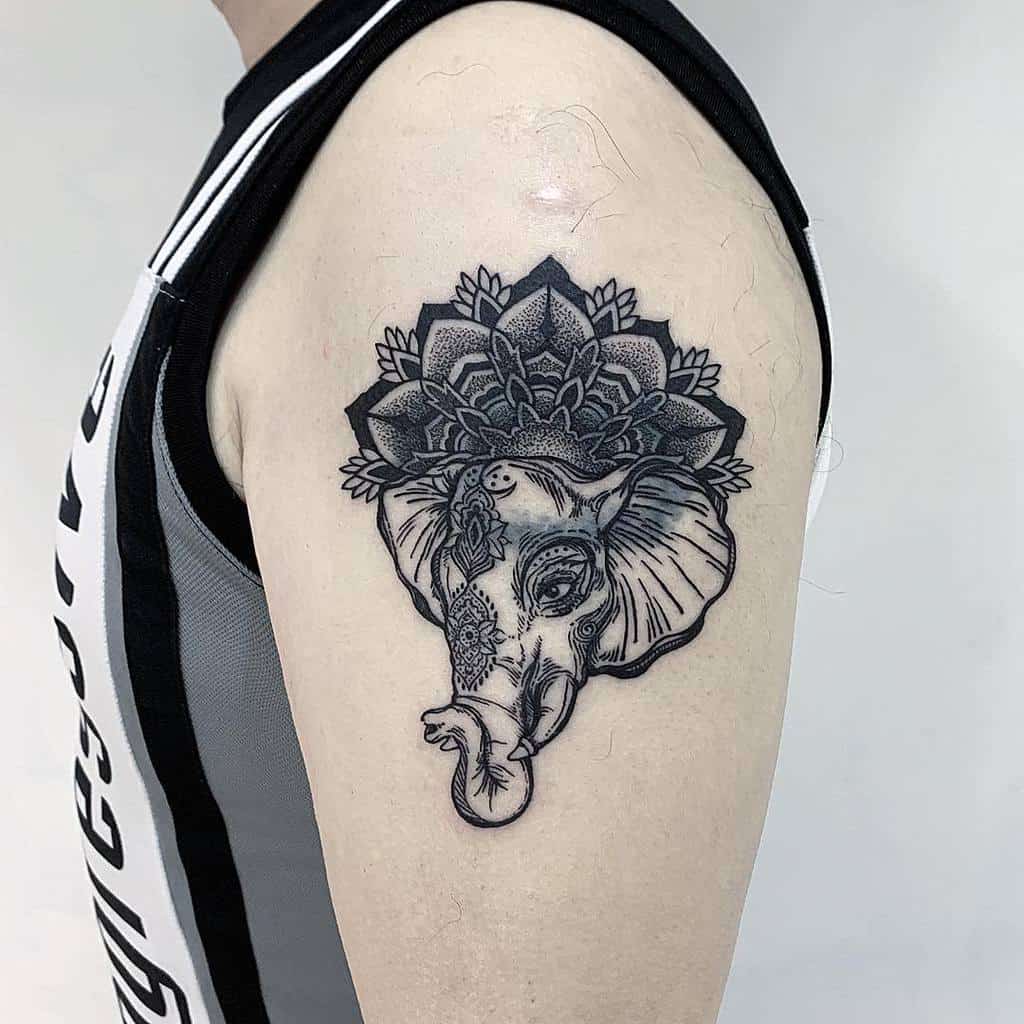 Elephant tattoo with floral and geometric patterns on an upper arm