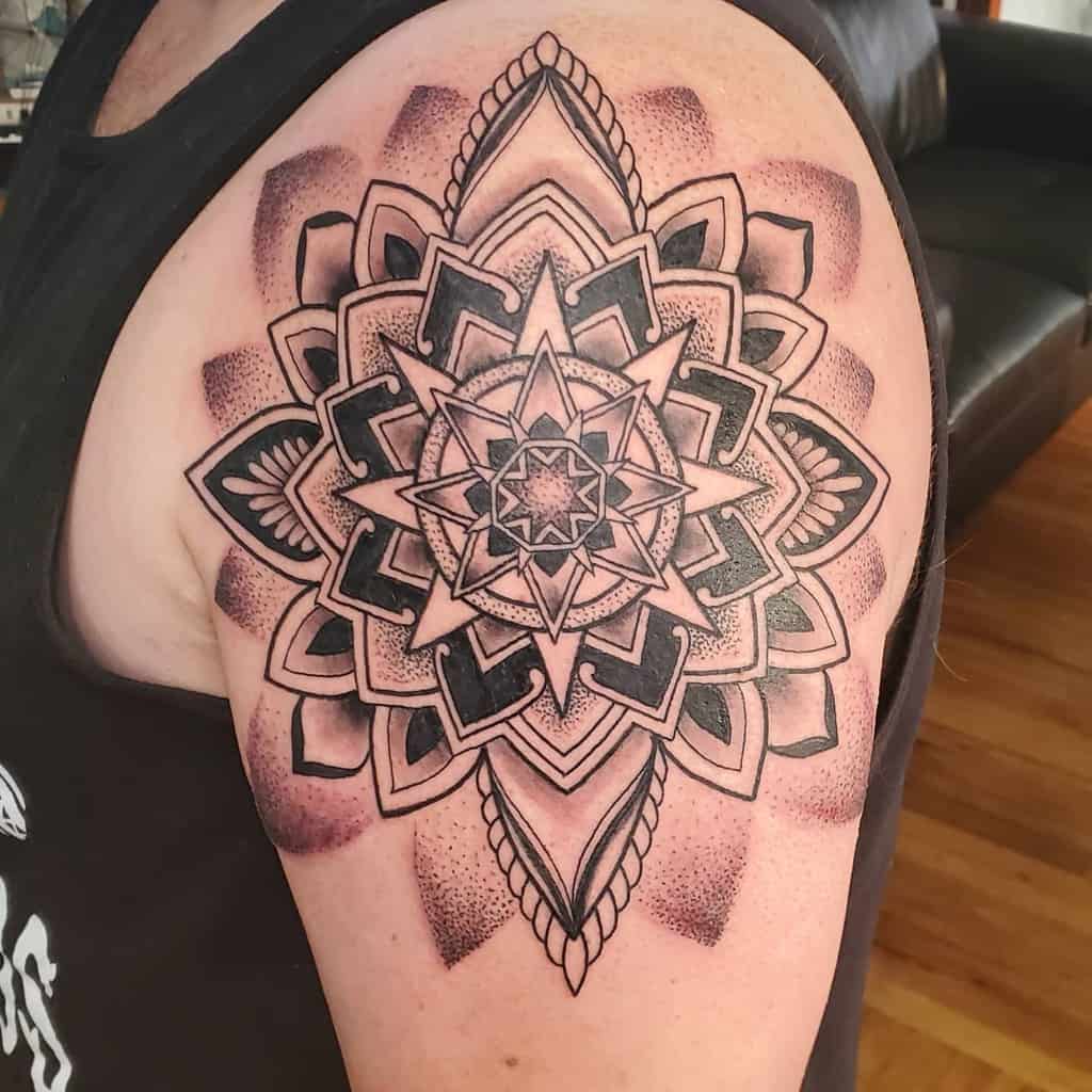 Ornate mandala tattoo on upper arm with intricate geometric design and shading