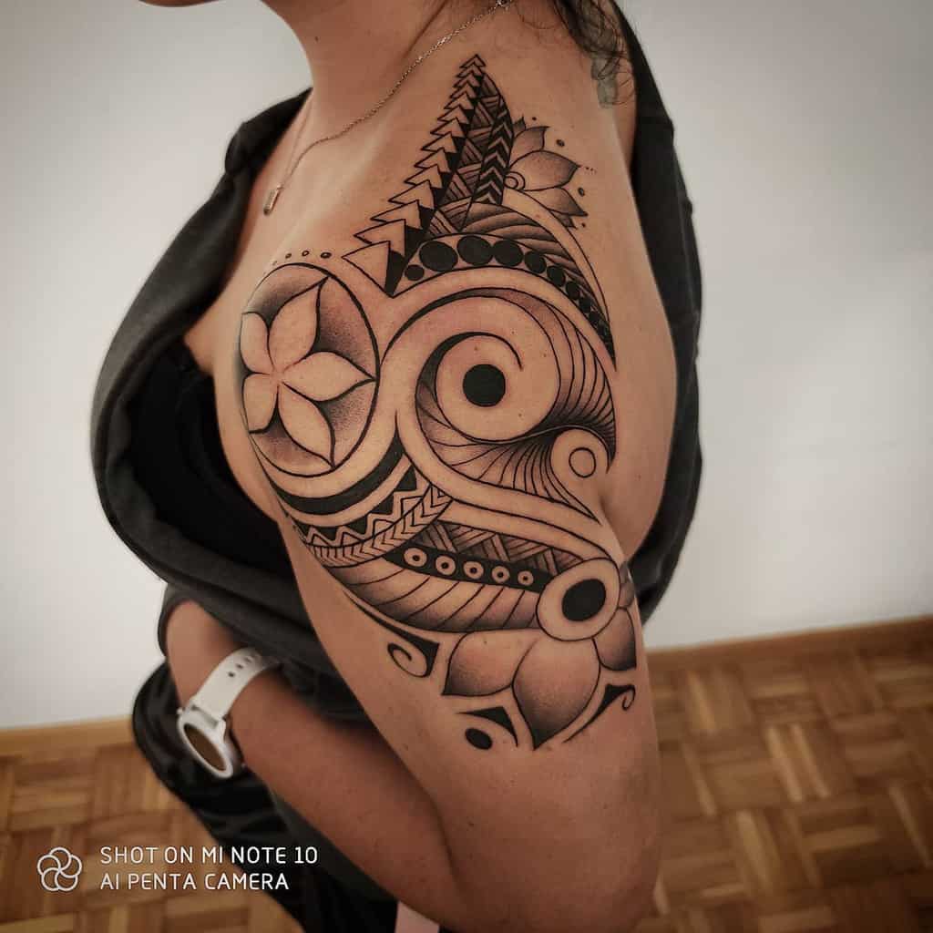 Woman with an intricate black tribal tattoo covering their upper arm and shoulder