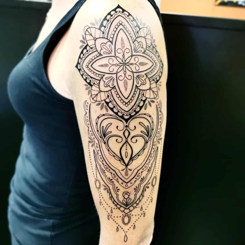 Intricate black mandala and floral tattoo on a woman's upper arm