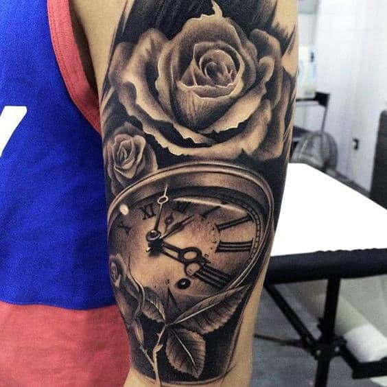 Arm tattoo of roses and a warped clock in black and gray ink