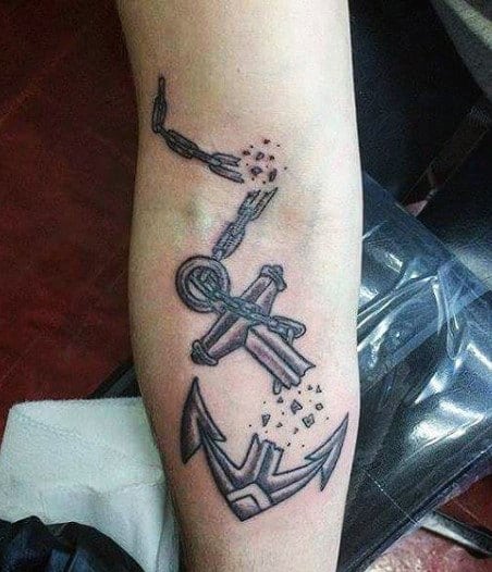 Tattoo of an anchor breaking into small pieces on a forearm