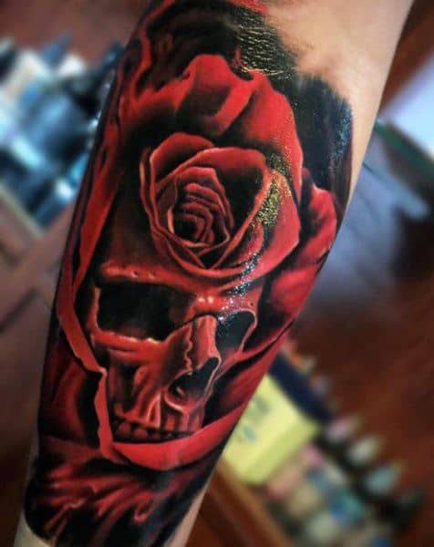 Bold tattoo of a skull emerging from a red rose, blending realism and surrealism with striking contrast and deep shading.