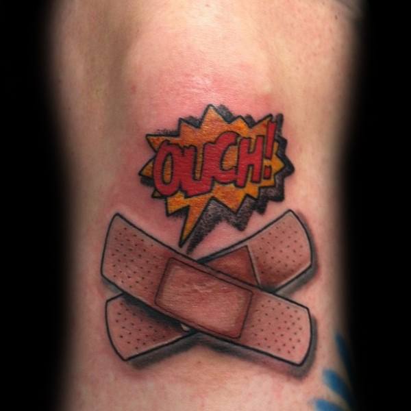 Crossed Band-Aid tattoo with a comic-style “OUCH!” above, featuring bold colors and playful cartoon-inspired shading.