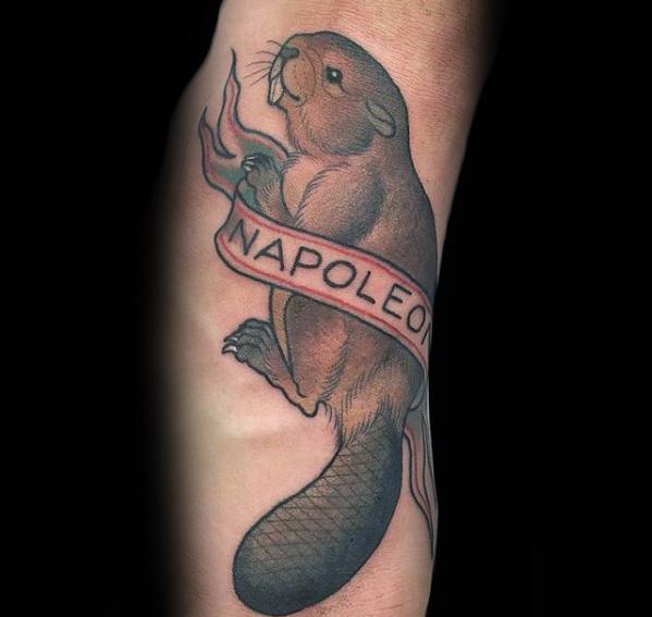 Classic-style beaver tattoo holding a flowing banner that reads “NAPOLEON,” with soft shading and a detailed tail.