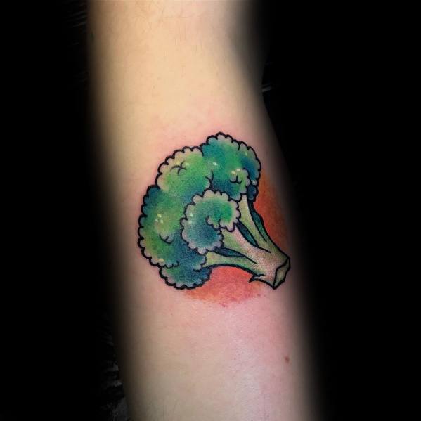 Colorful broccoli tattoo on the forearm, featuring bold outlines, vibrant shading, and a red background for a striking and playful design.