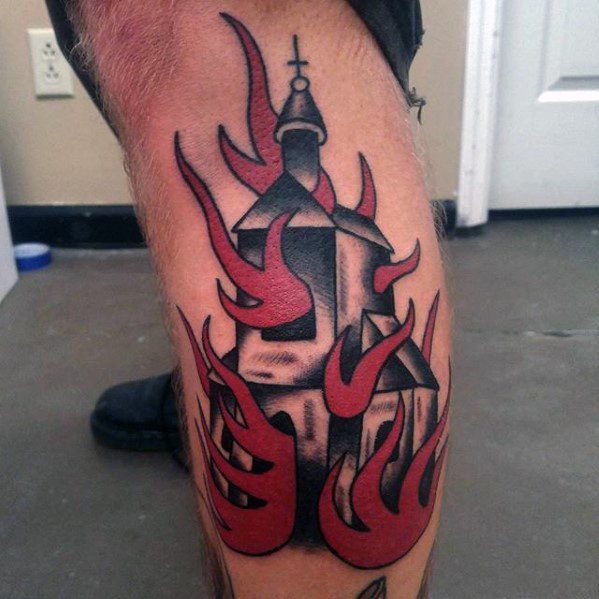 Bold black and red tattoo of a burning church on the leg. Thick red flames wrap around the structure with solid shading and sharp outlines.