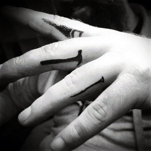 Minimalist finger tattoos of nails and a hammer, symbolizing strength, craftsmanship, and dedication to woodworking and construction.