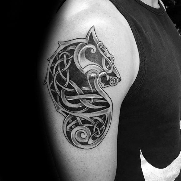 Celtic wolf head tattoo on upper arm with bold knotwork design and intricate curves forming a fierce and symmetrical shape.