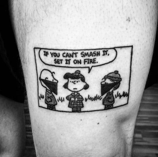 Black and white Peanuts-inspired tattoo featuring Snoopy, Lucy, and Charlie Brown in a rebellious scene with the quote, 'If you can't smash it, set it on fire.'