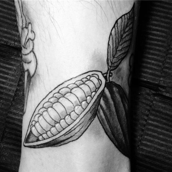 This black and gray tattoo depicts a realistic cacao pod with intricate shading, highlighting the natural texture of the cocoa beans inside.