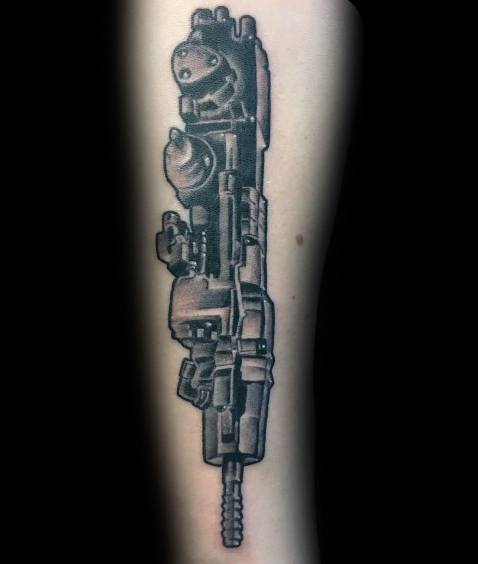 Black and grey tattoo of a detailed jackhammer or coal mining drill placed vertically on the forearm.