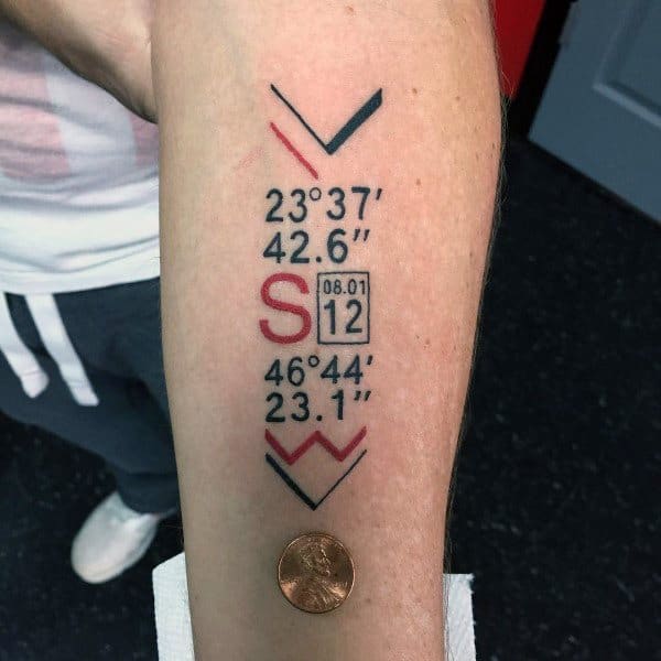 Bold geometric coordinate tattoo on the forearm with black and red accents, featuring arrows, numbers, and a date box, symbolizing a special location.
