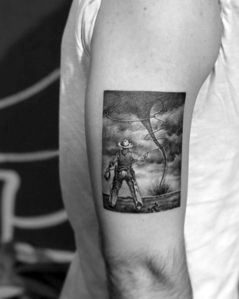 Black and gray tattoo of a cowboy facing a tornado, holding a lasso, done in a realistic style with fine shading and dramatic contrast.