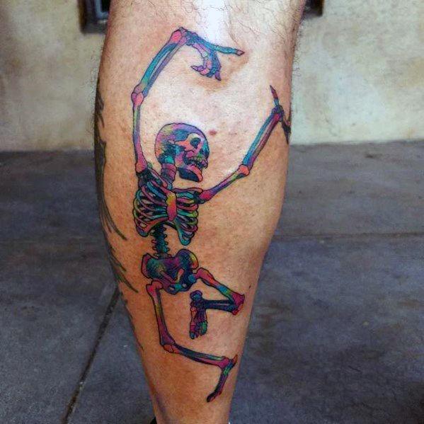 Colorful dancing skeleton tattoo with neon hues and bold outlines, creating a vibrant and dynamic design on the calf.