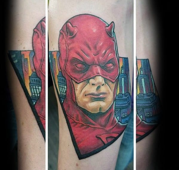 Vibrant Daredevil tattoo with comic-style lines, a serious expression, and a cityscape background framed in a sharp black triangle.