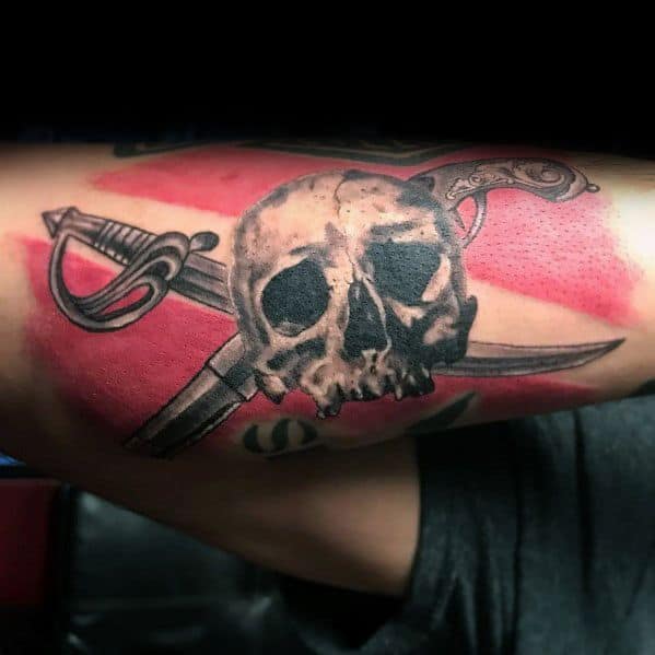 Tattoo of a skull with crossed swords over a red and white dive flag, symbolizing adventure, danger, and a fearless spirit of the sea.