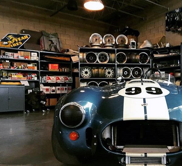 Classic car workshop featuring automotive parts and a vintage Shelby Cobra.