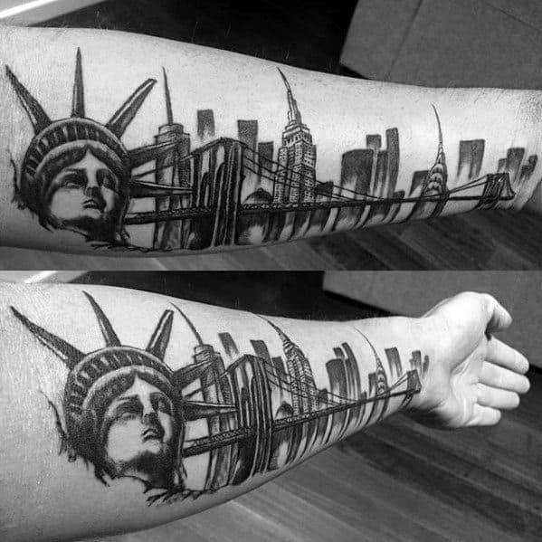 Empire State Building tattoo with Statue of Liberty and Brooklyn Bridge, detailed across a man's inner forearm in bold black shading.