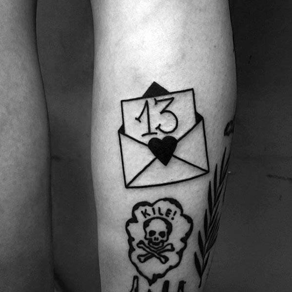 Tattoo of an envelope with "13" and a heart, plus a skull