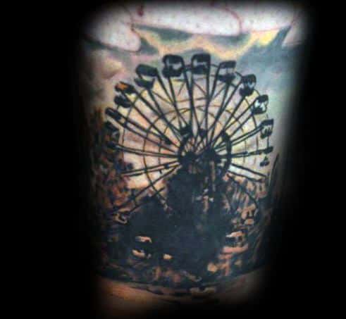 Dark-themed Ferris wheel tattoo with heavy shading, a moody atmosphere, and cloudy skies, creating a nostalgic and eerie amusement park scene.