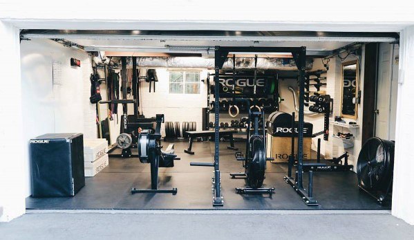Well-equipped garage gym with cardio machines, power rack, plyo box, and weightlifting gear.