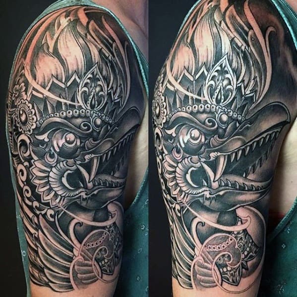 Garuda tattoo design with intricate details, sharp teeth, and bold shading, extending from shoulder to upper arm.