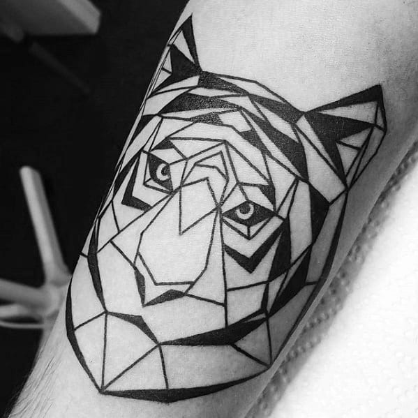 Bold geometric tiger tattoo with sharp black linework and angular shapes, forming a striking and symmetrical tiger face on the arm.