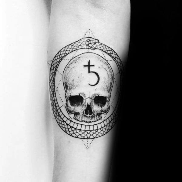 Black and grey tattoo featuring a skull with an alchemical symbol on its forehead, encircled by an ouroboros snake and geometric elements.
