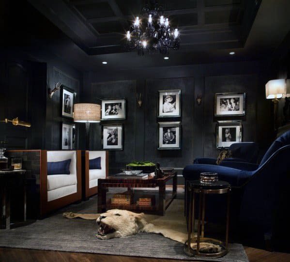 Dark, elegant man cave with plush furniture, framed photos, chandelier, and a lion rug on the floor