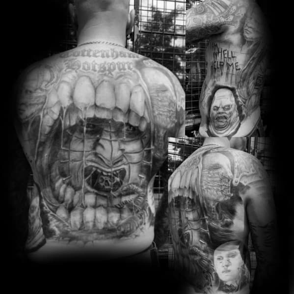 Black and grey *Hellraiser* full-back tattoo featuring a screaming face within a grotesque tooth-filled frame, eerie characters, and haunting details.