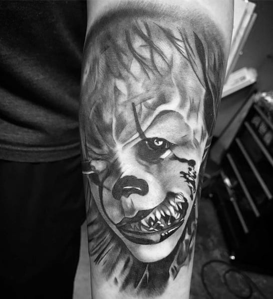 Black and grey tattoo of Pennywise the Clown with a menacing grin, sharp teeth, and intense shading for a haunting horror look.