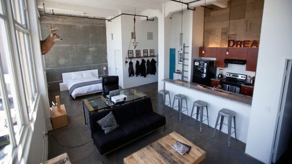 Industrial-style studio with open layout, modern kitchen, and rustic wooden furniture.