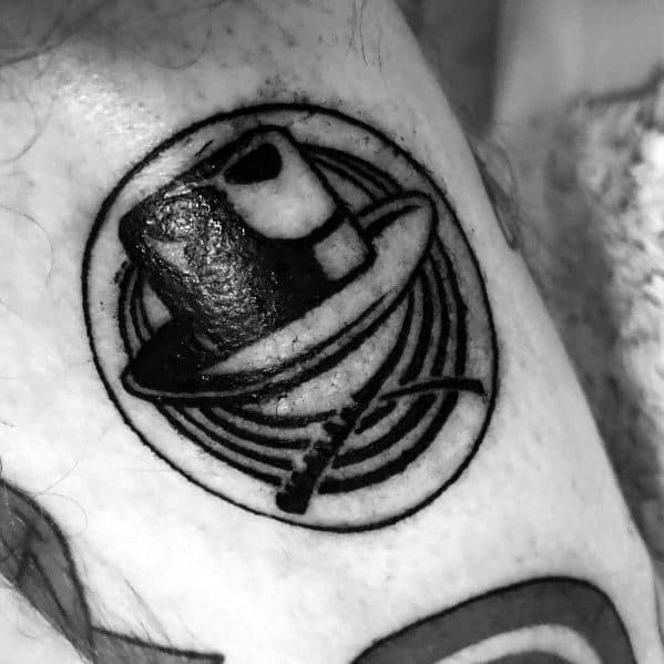 Minimalist black ink tattoo featuring Indiana Jones' iconic fedora and whip inside a circular design with concentric lines.
