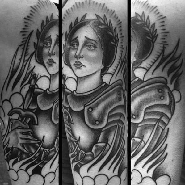 Black and grey Joan of Arc tattoo with stylized flames, clouds, and armor, portraying a calm yet powerful expression with a sword.