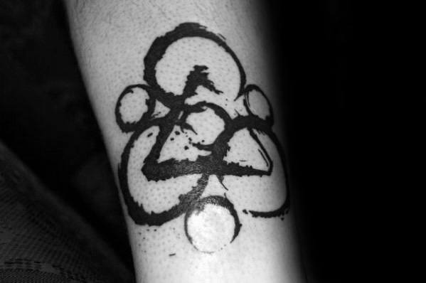 Coheed and Cambria Keywork tattoo in bold black ink with a splattered brushstroke effect, placed on the forearm for a striking look.