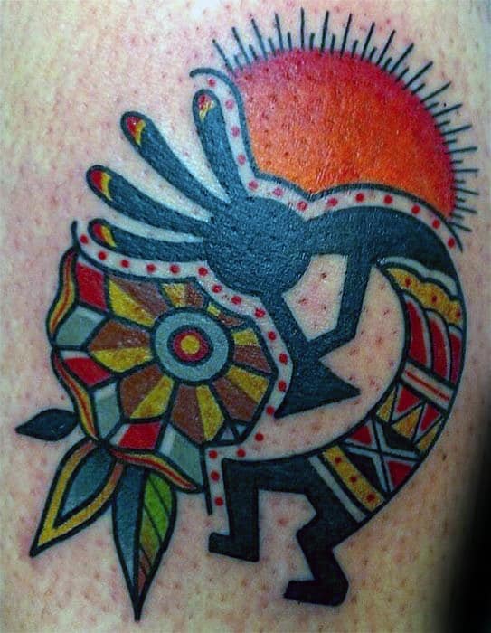 Vibrant Kokopelli tattoo with bold colors, featuring a sun, intricate flower patterns, and tribal accents that reflect Native American symbolism.