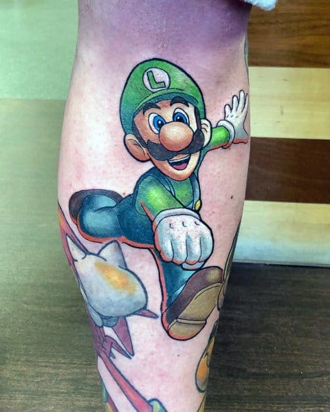 Colorful tattoo of Luigi in a dynamic jumping pose with an excited expression, featuring detailed shading and vibrant colors on the leg.