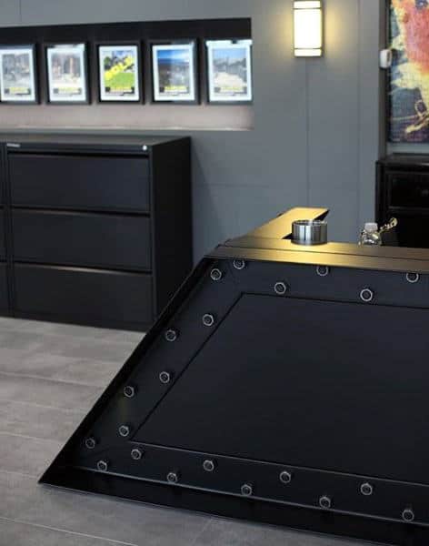 Sleek black desk with industrial design in a modern office; framed pictures hang on the wall in the background