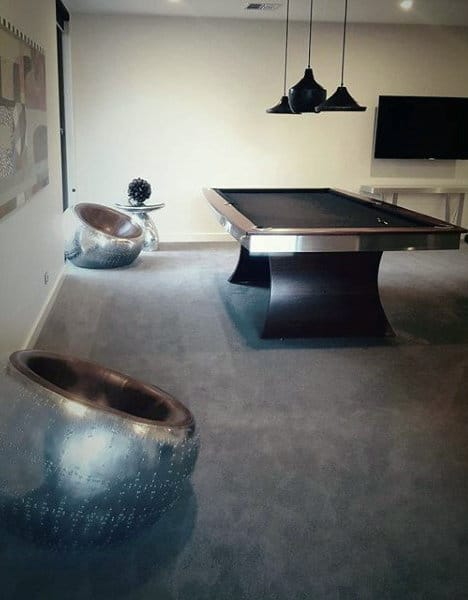 Modern game room with a pool table, metallic chairs, pendant lights, and a wall-mounted TV