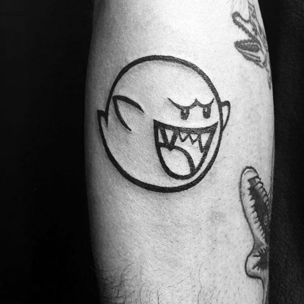 Minimalist Mario ghost tattoo featuring Boo with a playful grin and tongue out, inked in bold black outline on the forearm.