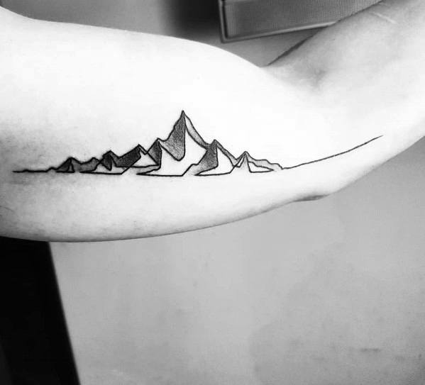 Minimalist mountain tattoo on the inner forearm, featuring a continuous thin line forming sharp peaks for a sleek and modern landscape design.