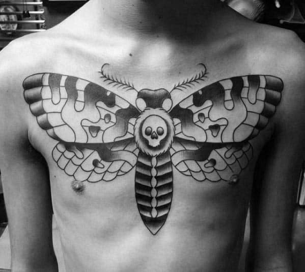 Black and white chest tattoo of a large moth with a skull design on a chest