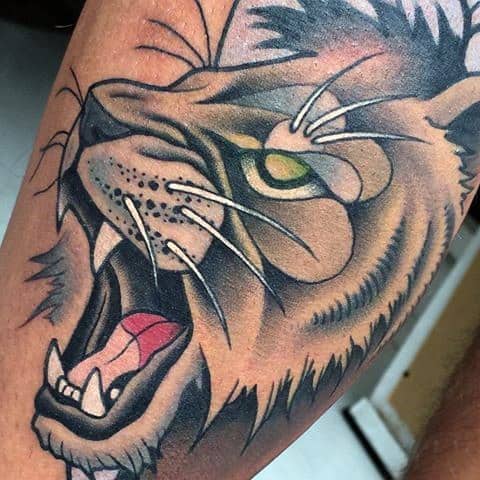 Neo-traditional roaring lion tattoo with a vivid green eye, sharp teeth, and bold shading for an intense and powerful design.